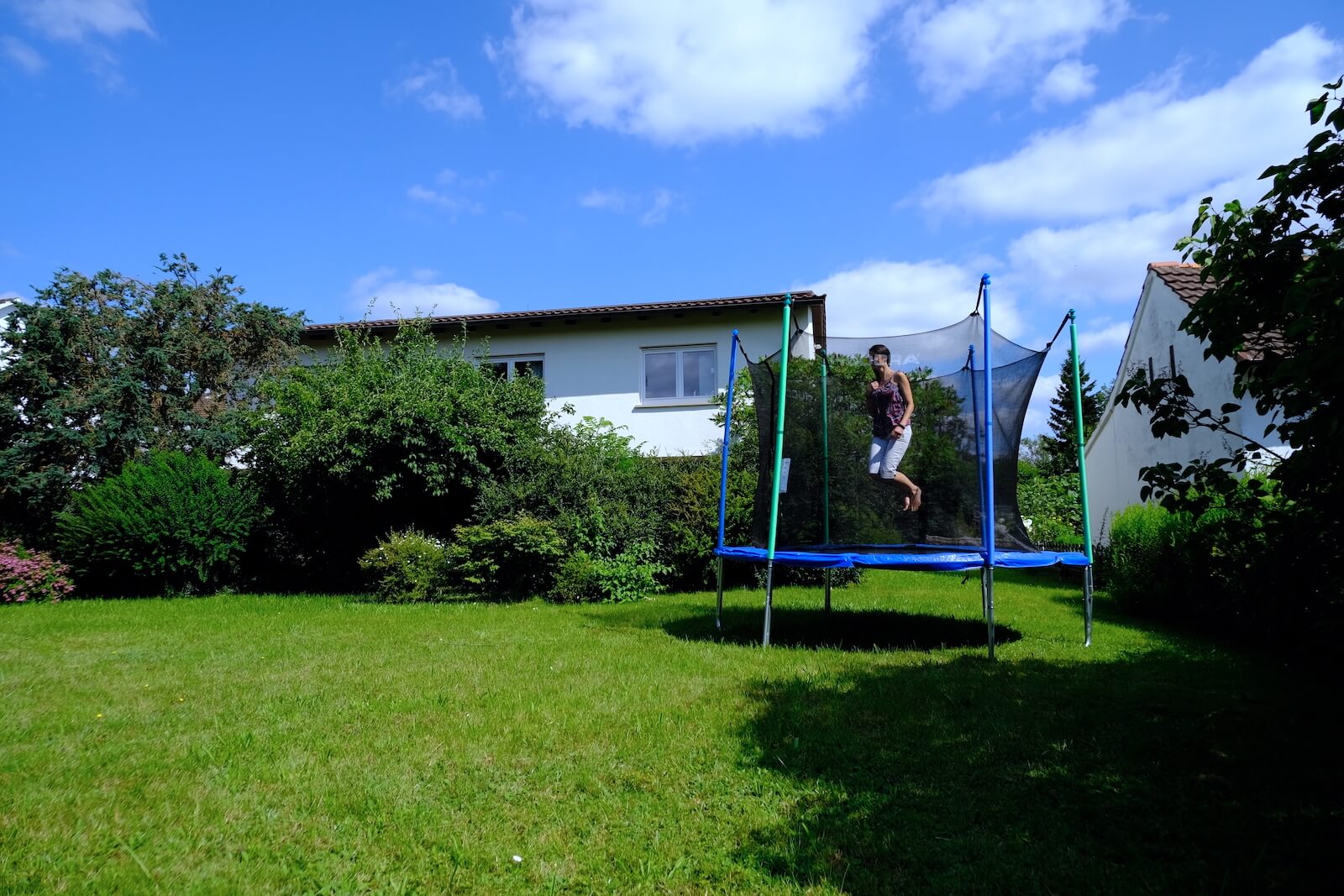 Jemand springt auf dem großen Trampolin im Garten des Therapie-Zentrums