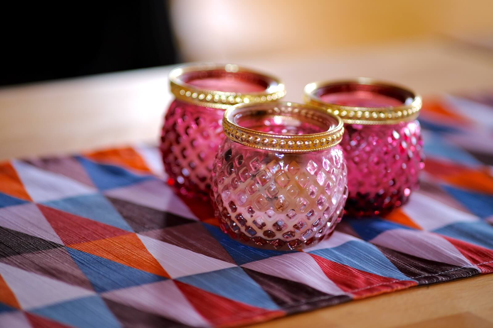 Teelichter in rosa Gläsern auf einer bunten Tischdecke